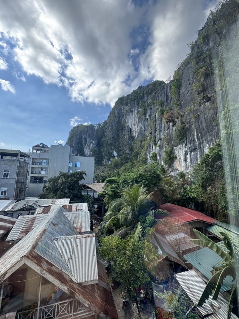 Towering limestone cliffs looming over El Nido rooftops and town