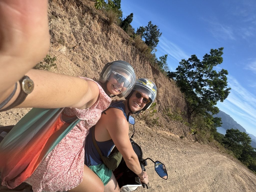 Meg and Ryker selfie on a scooter on a mountain dirt road in Coron