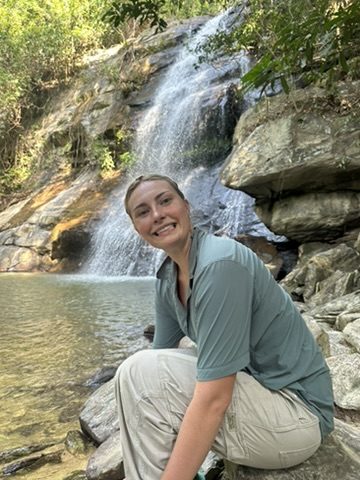 Meg sitting on rocks in front of a waterfall near Port Barton