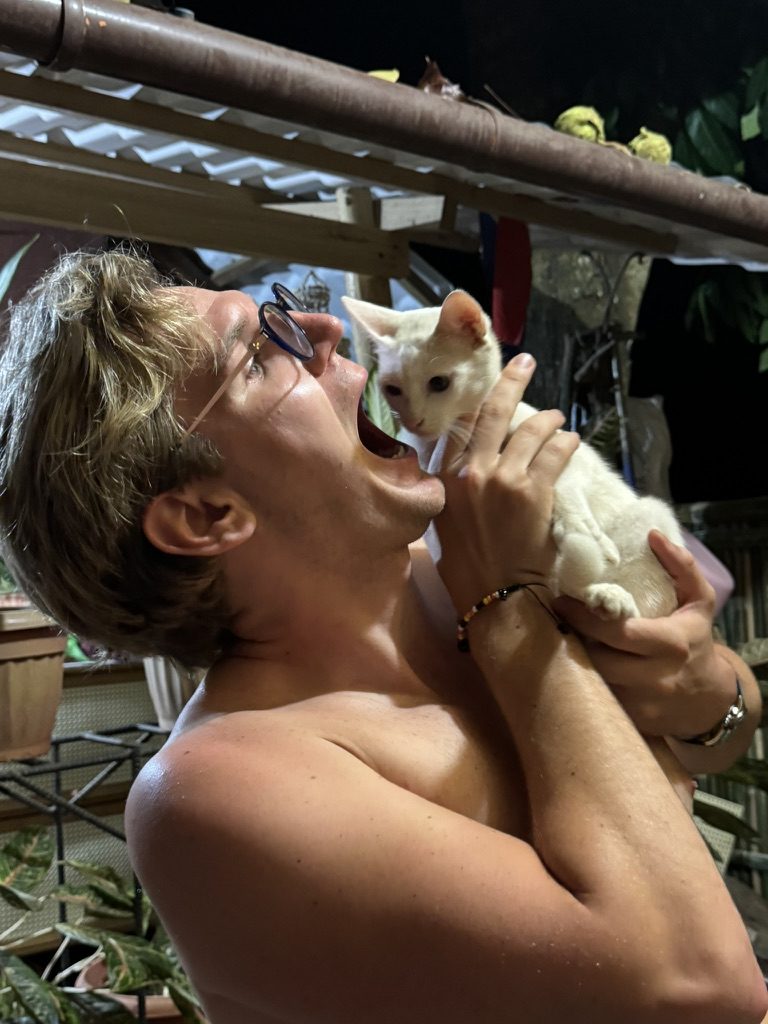 Miles holding the rambunctious Airbnb kitten up to his face with delight
