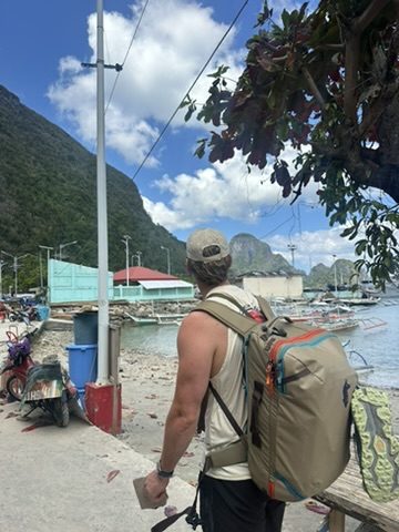 Ryker with backpack looking out at El Nido harbor and boats