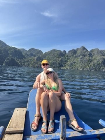 Ryker and Meg sitting together on the bow of the island hopping boat with limestone karst islands behind them