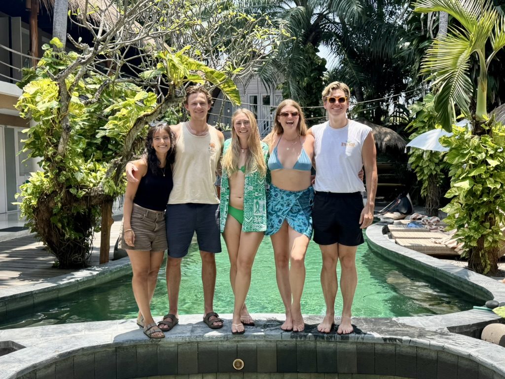 Group of five friends standing at the edge of the KIMA pool in the sunshine — Laurens, Ryker, Meg, Anna, and Fraser