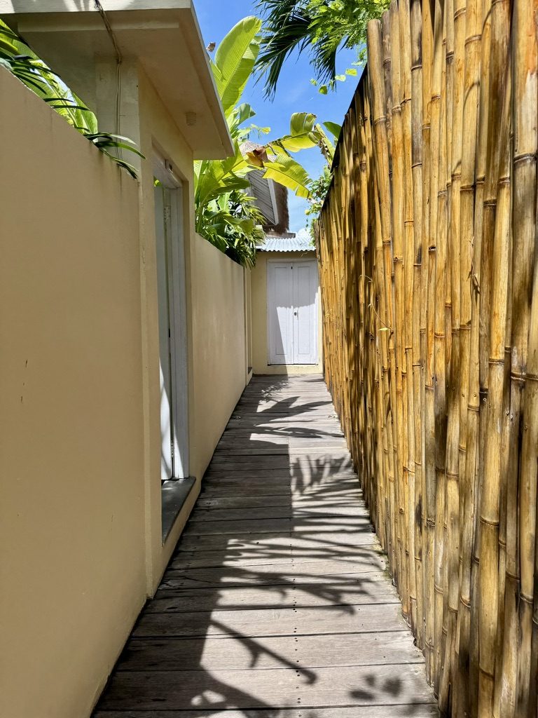 Beautiful bamboo and white-walled walkway at KIMA surf camp with tropical plants