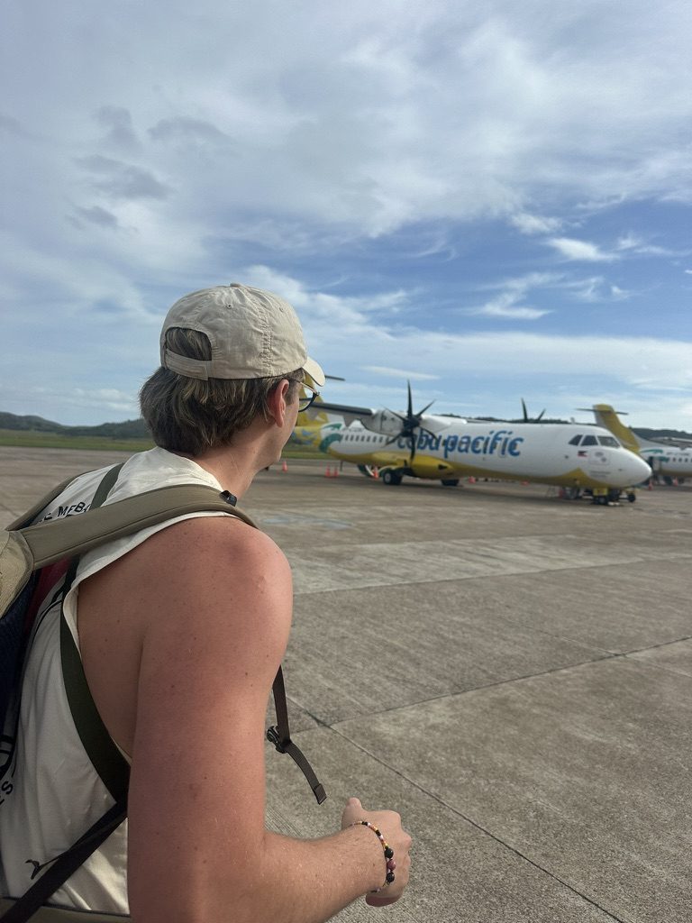Ryker at the tarmac looking at a Cebu Pacific propeller plane, leaving the Philippines