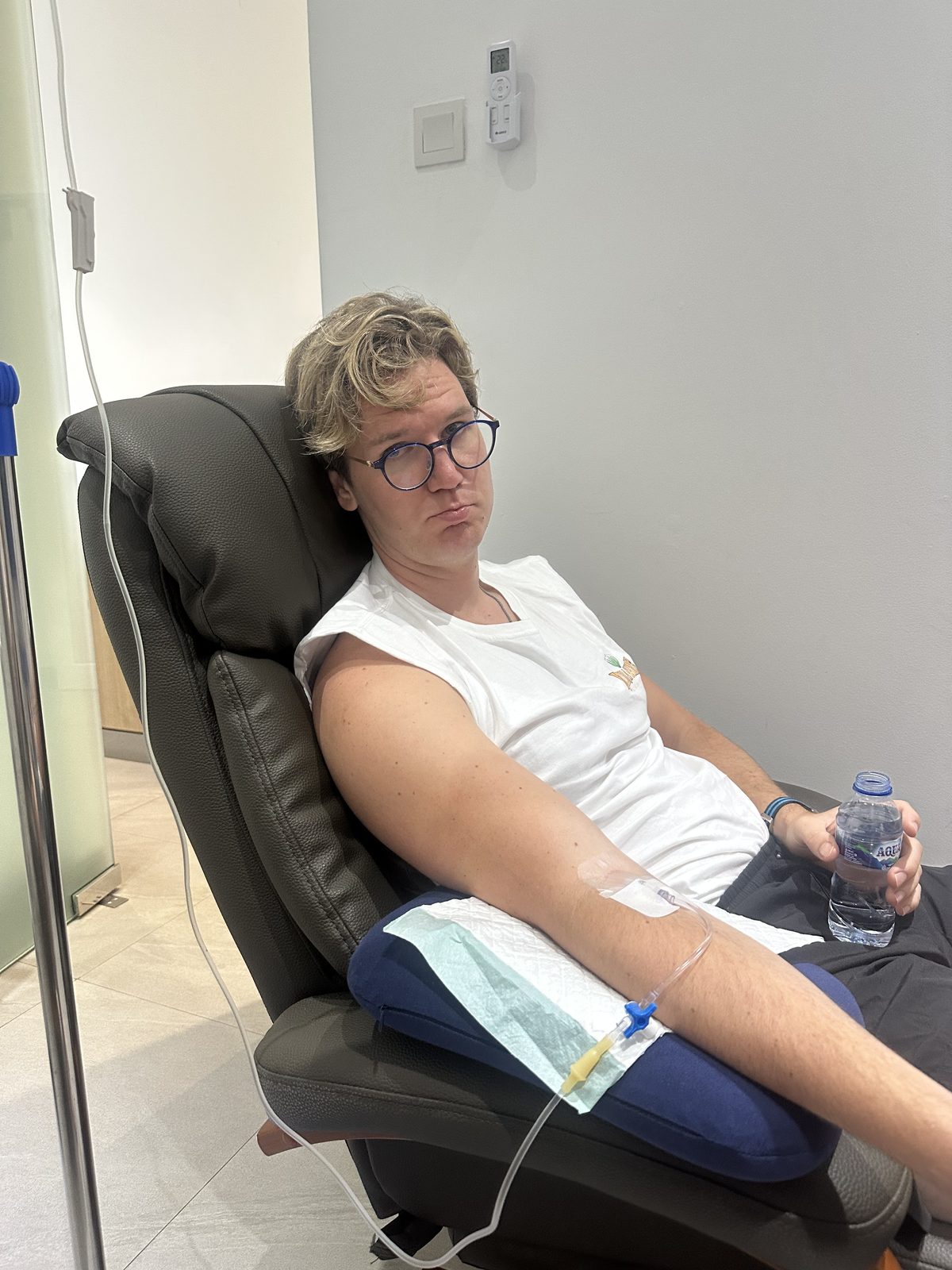 Ryker in the clinic recliner chair with an IV in his arm, looking deeply unimpressed