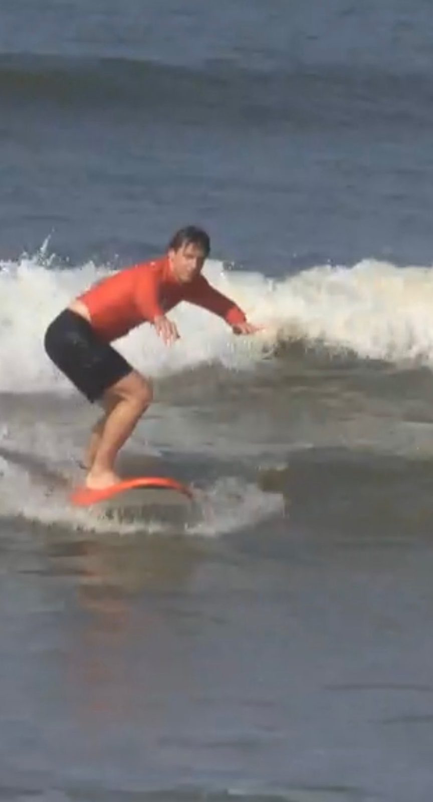 Ryker riding a wave on his surfboard in the murky brown Bali surf