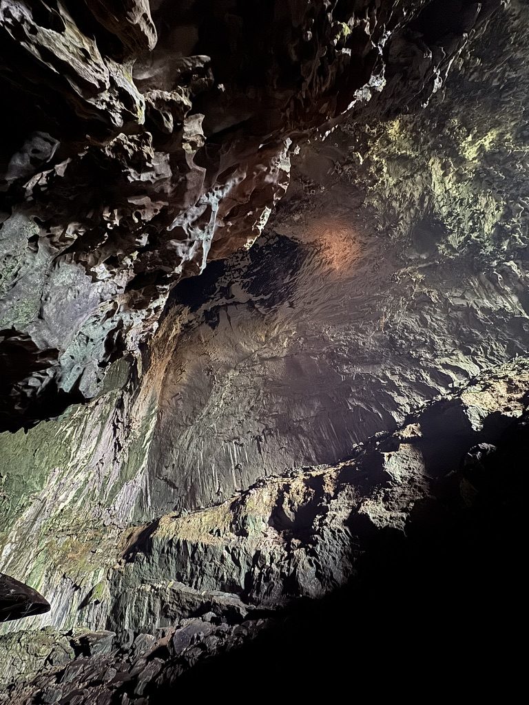 Dramatic cave ceiling with ancient stalactite formations lit in amber and gold