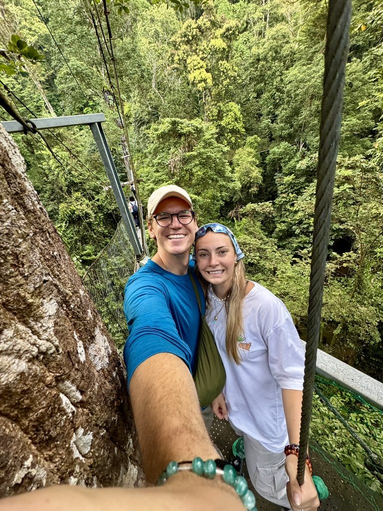 Ryker and Meg selfie on the canopy walkway high above the jungle floor, dense green below