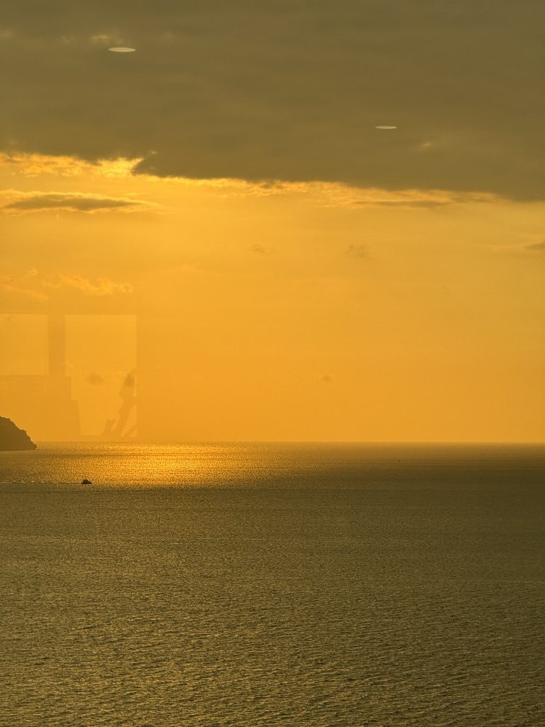 Molten golden sunset over the South China Sea from Kota Kinabalu, lone fishing boat silhouetted on the glowing water