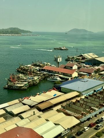 Aerial view of Kota Kinabalu harbor with fishing boats, waterfront warehouses and islands in the distance