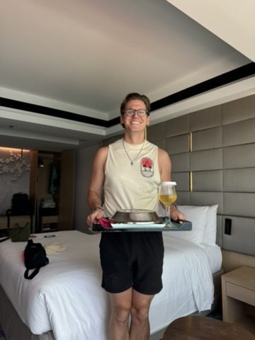 Ryker holding the hotel welcome drink tray with a big grin in the Mulu suite