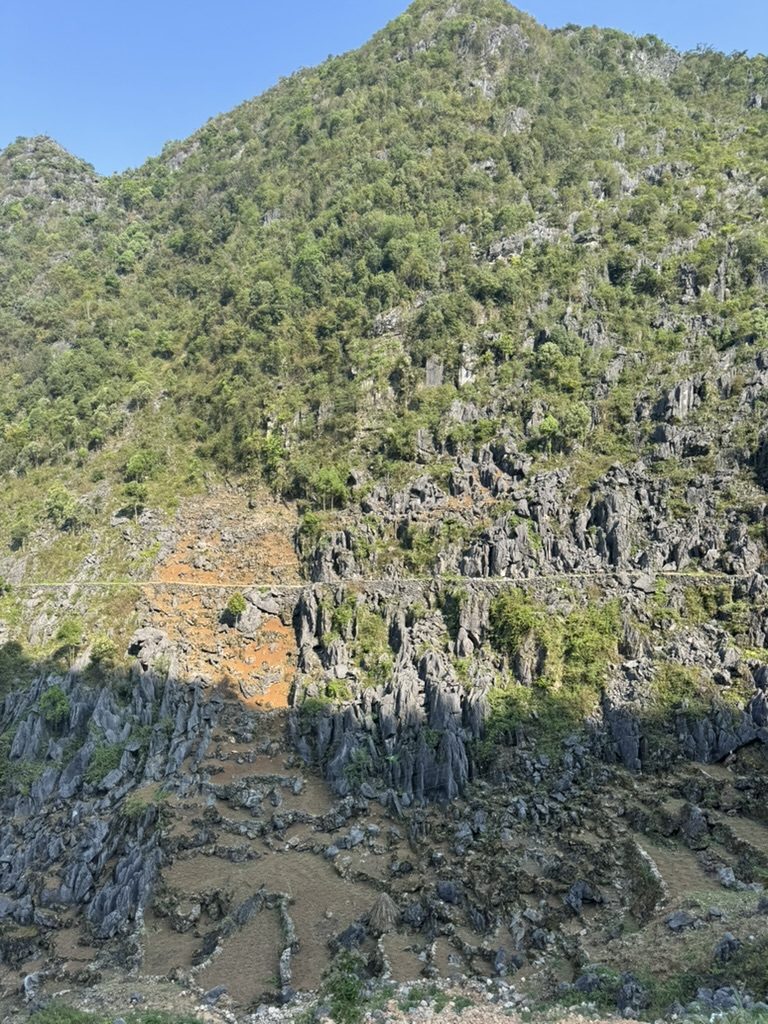 The Ha Giang Loop cliff road with a tiny white line carved into the rock