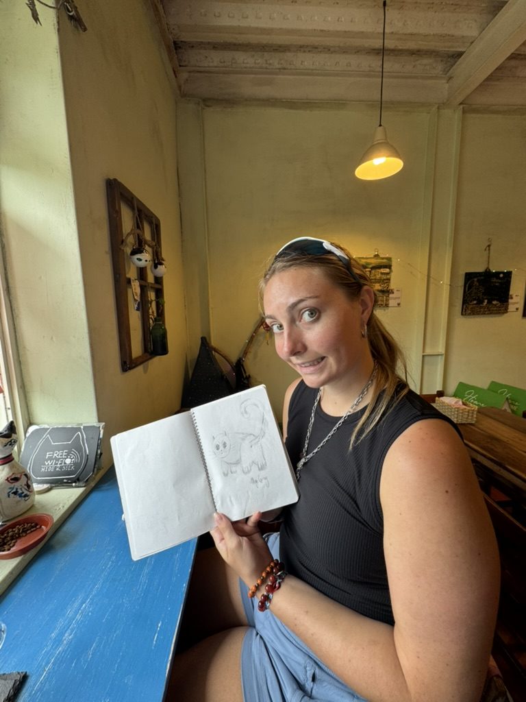 Meg at the cat village cafe with her cat drawing