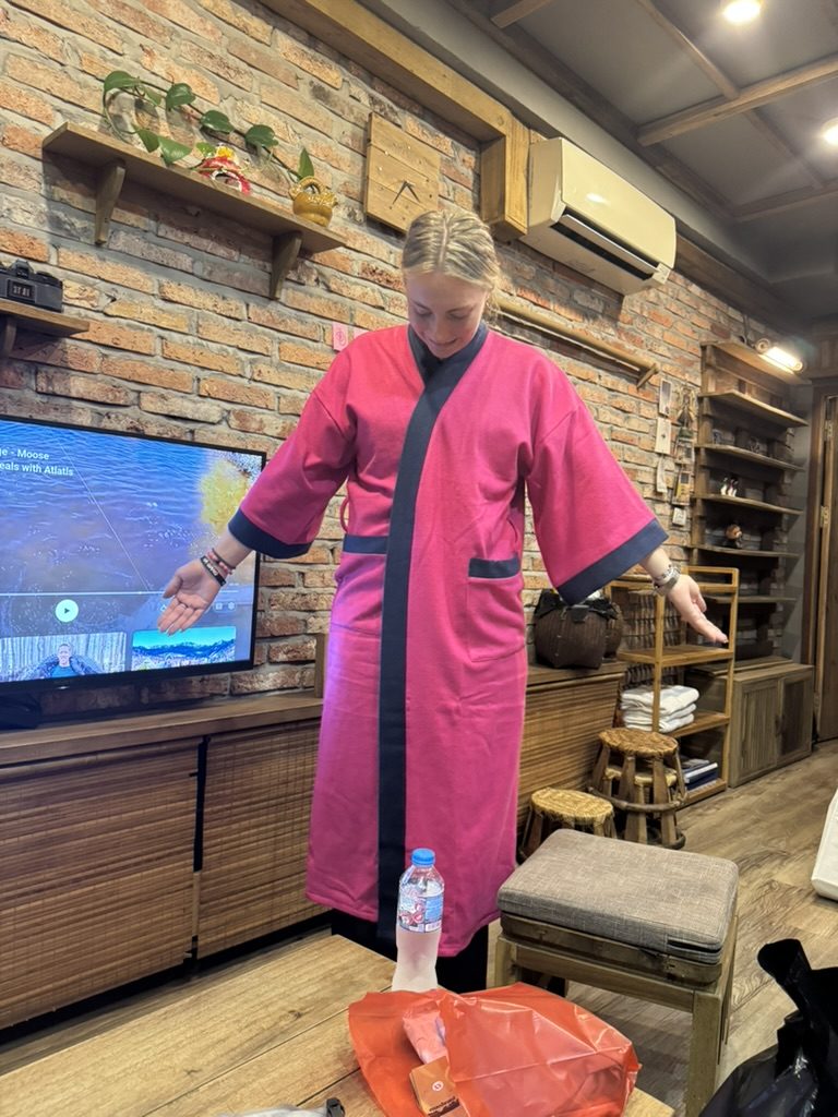 Meg trying on a pink silk robe at a Hanoi shop