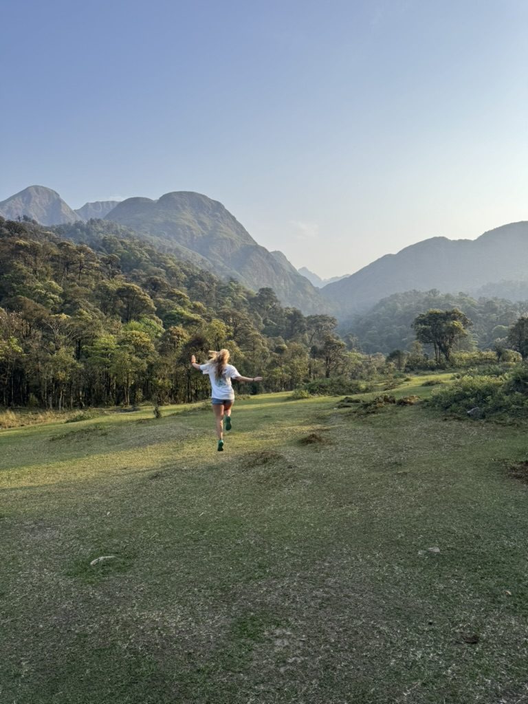Meg running through the Sapa valley with mountains behind her