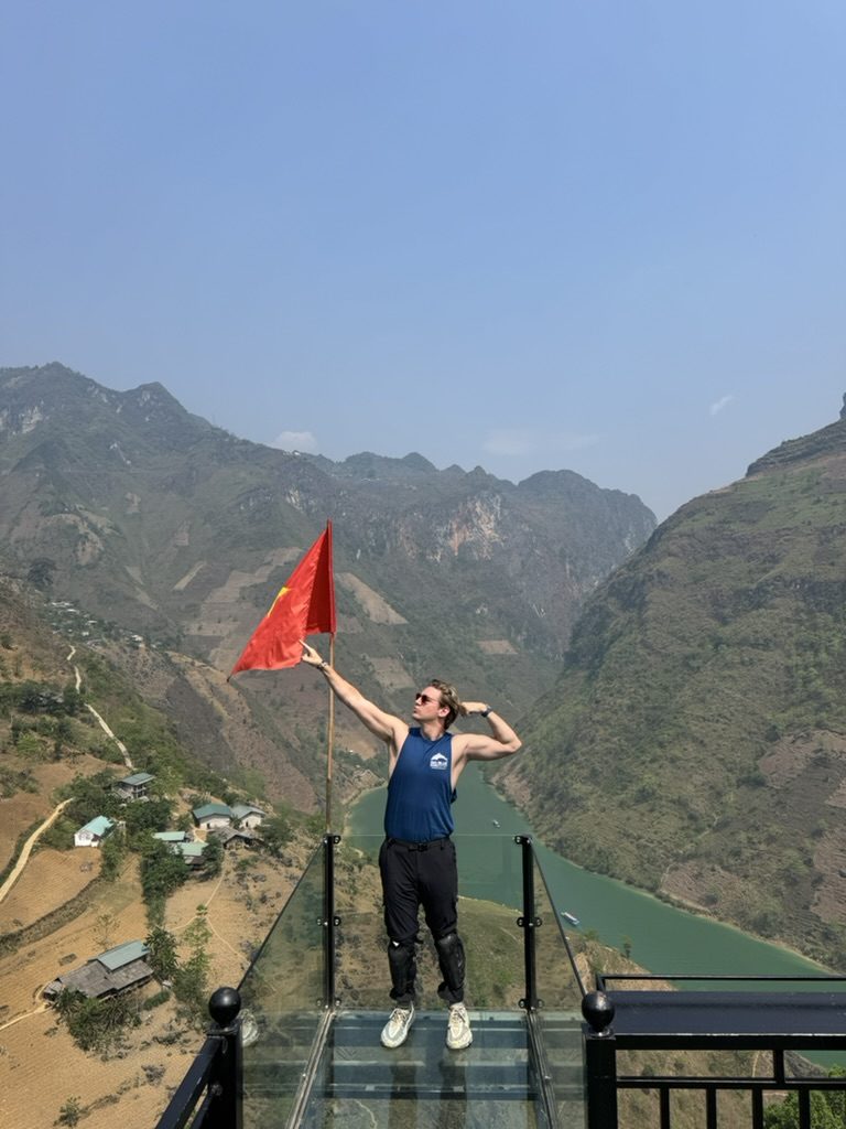 Ryker posing with the Vietnam flag on the Ha Giang glass platform