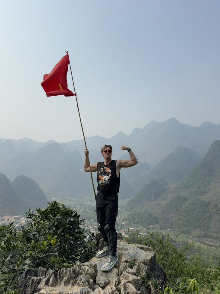 Ryker flexing with the Vietnam flag on a rocky peak