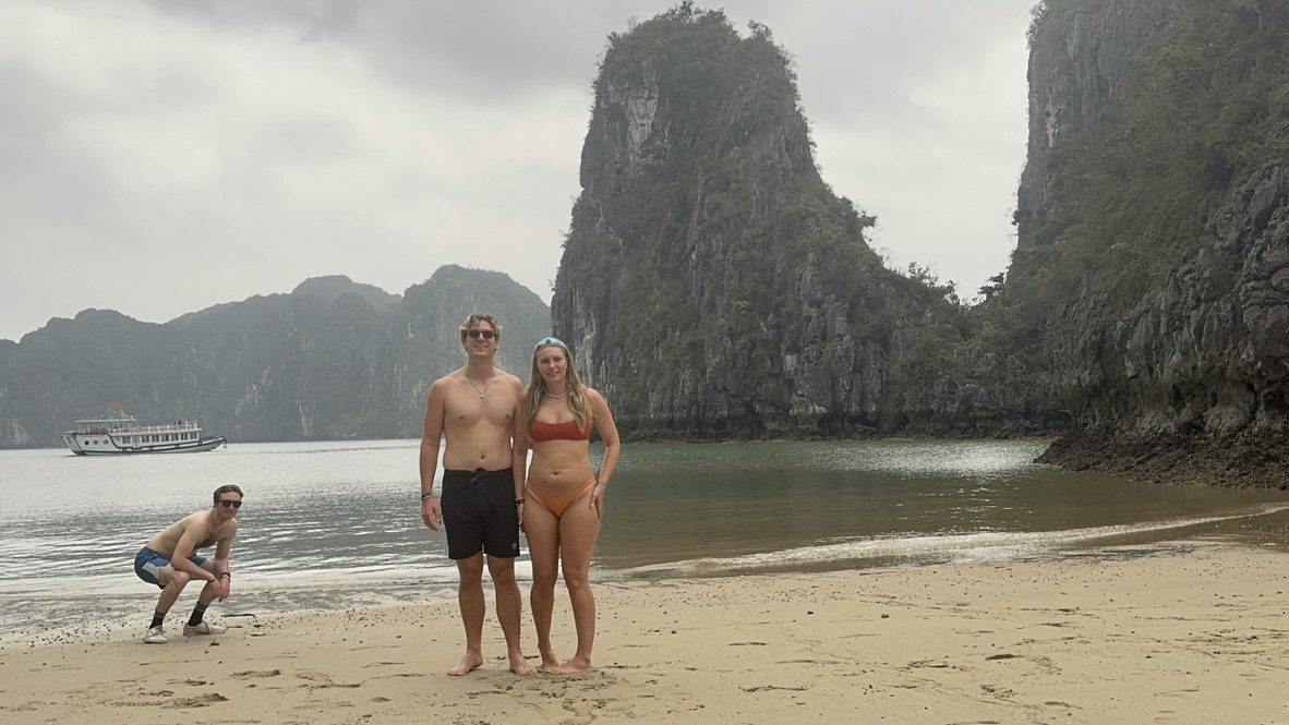 Ryker and Meg on the Ha Long Bay beach with karst towers behind