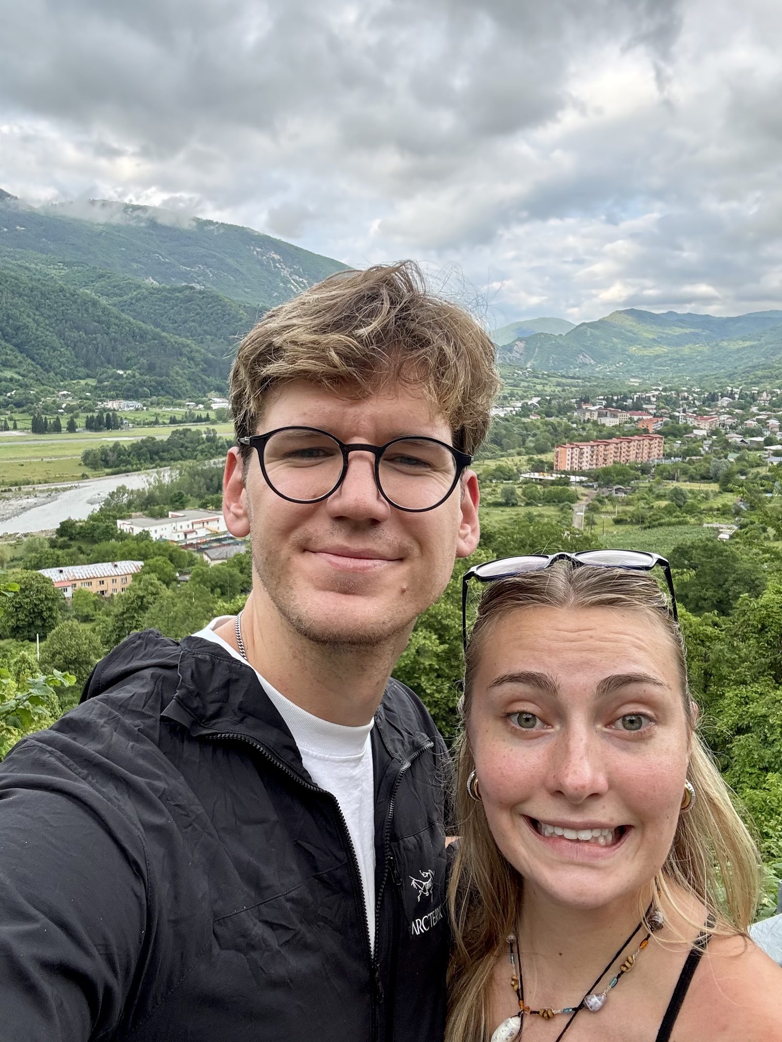 A couple selfie above a green Georgian valley