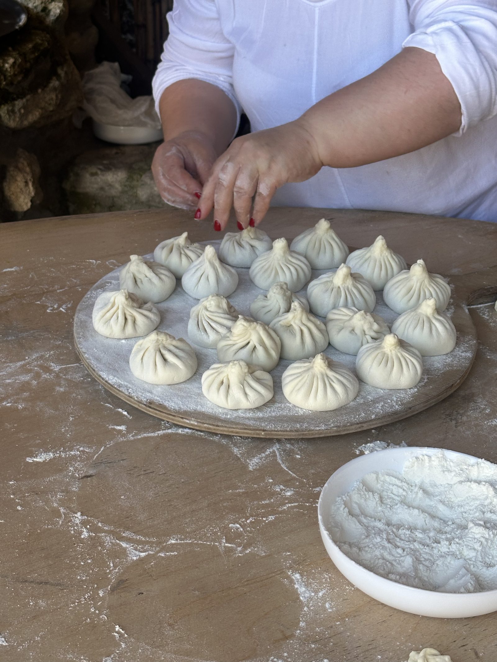 Hands folding fresh khinkali dumplings