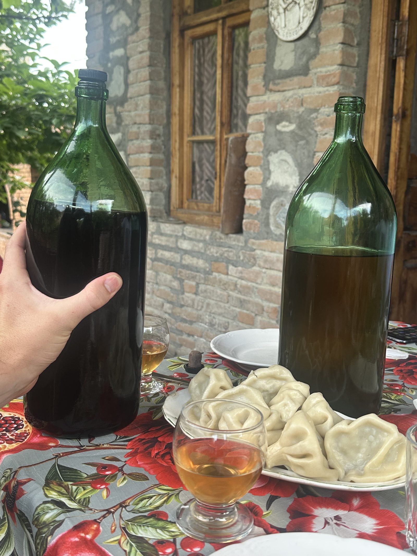 Homemade wine jugs beside a plate of khinkali