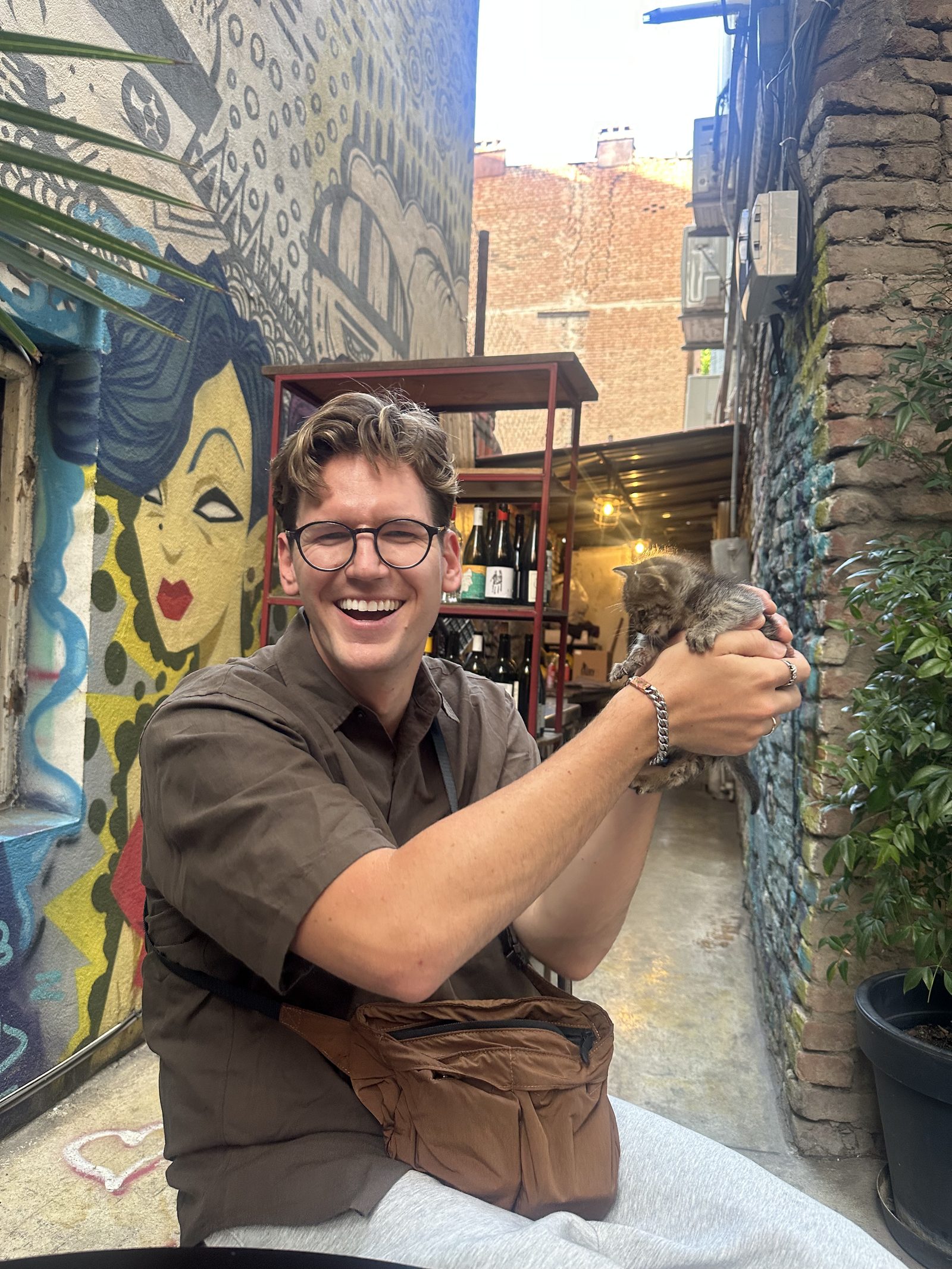 Cradling a cat in a graffiti-covered courtyard