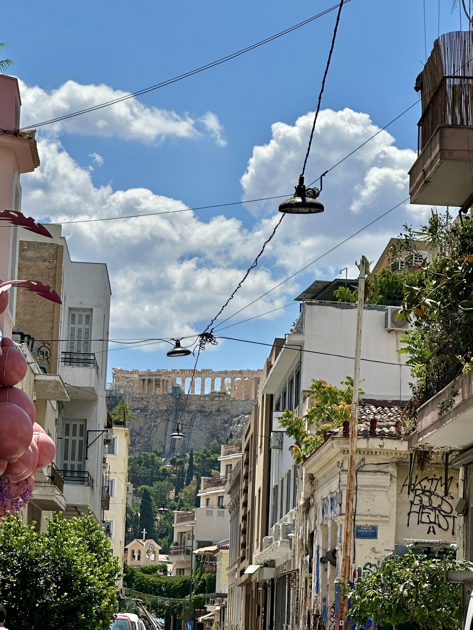 The Acropolis ruins in the background of a street with clouds and sky