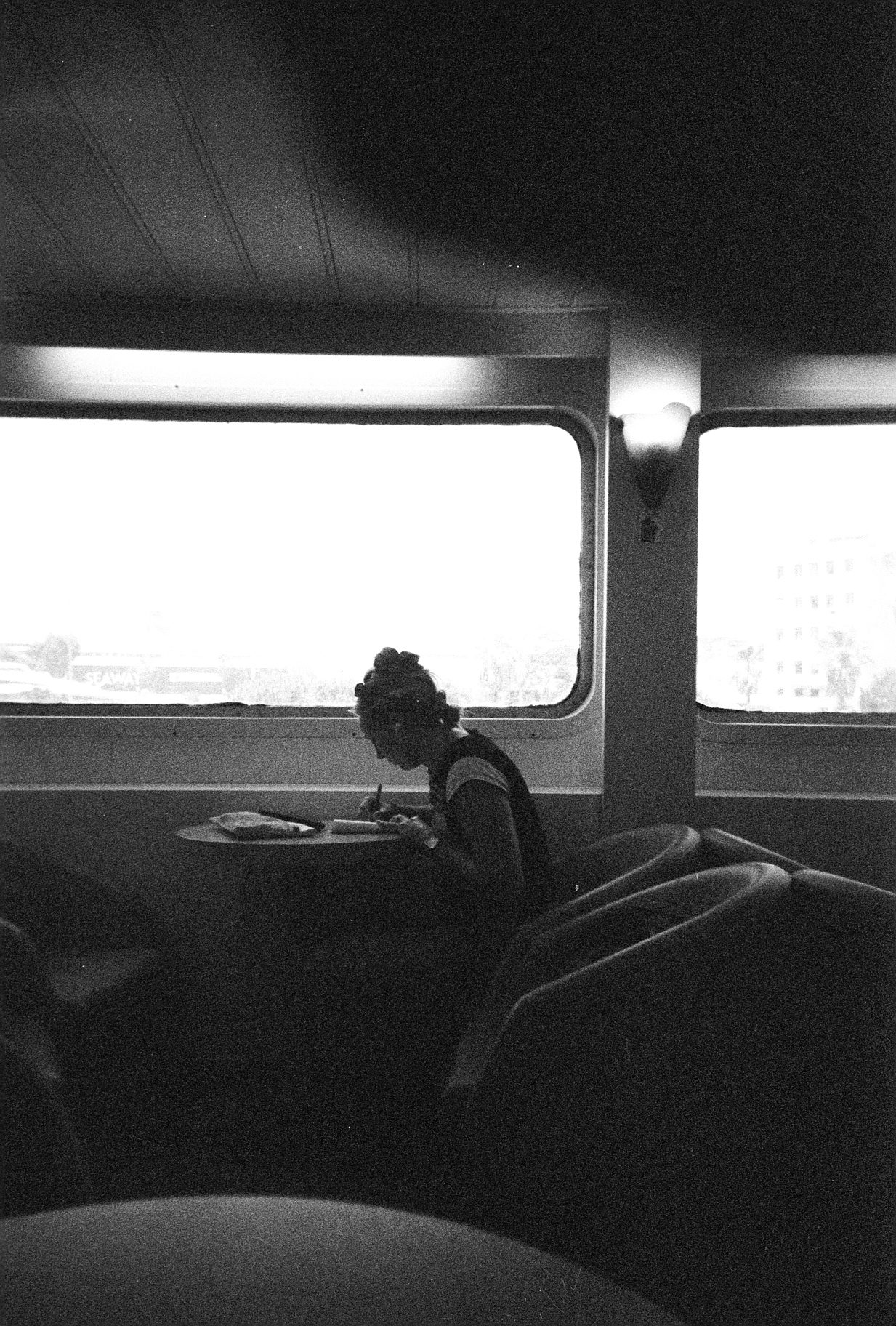 Black and white film photo of someone writing on the ferry