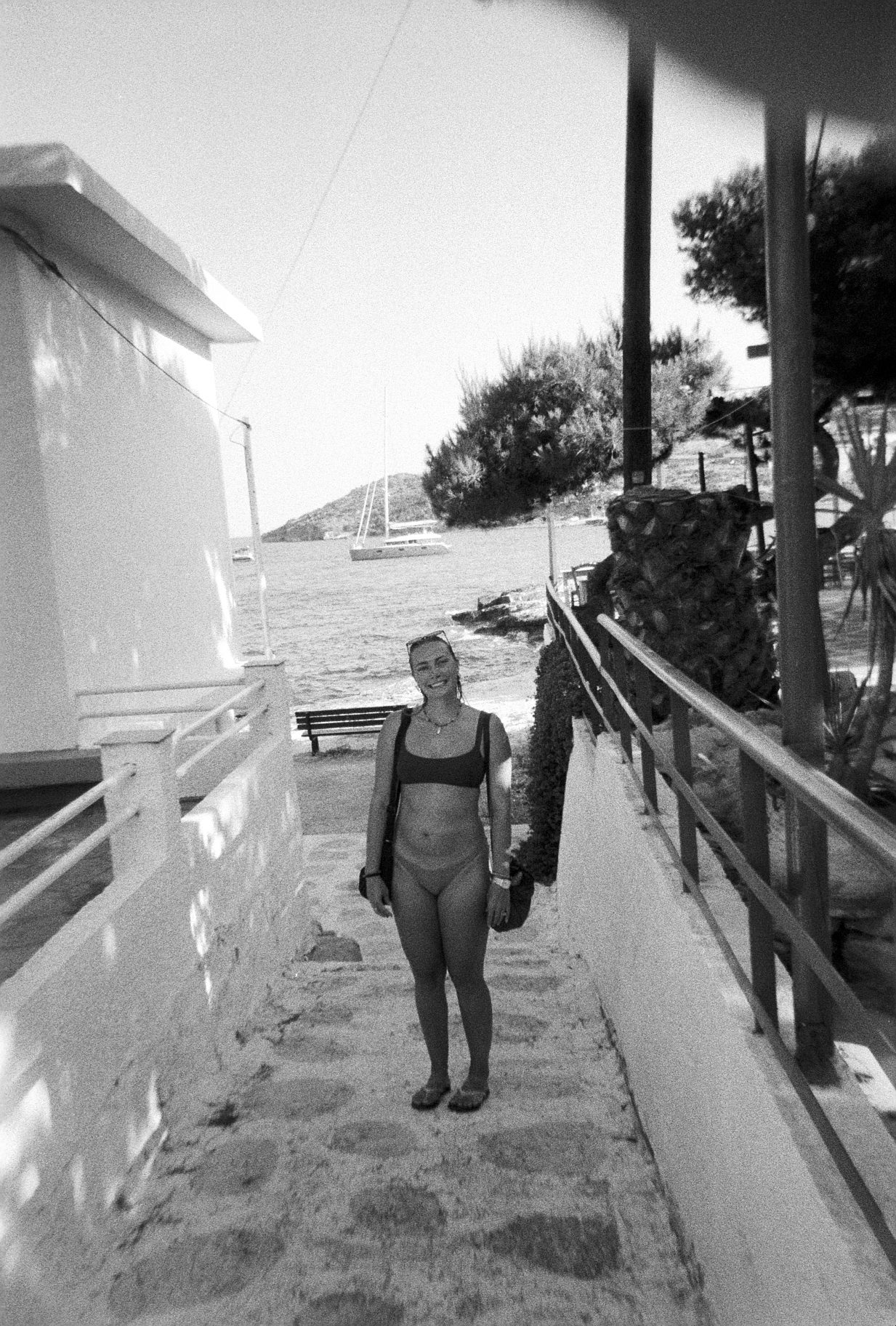 Black and white film photo of Meg walking along the dock