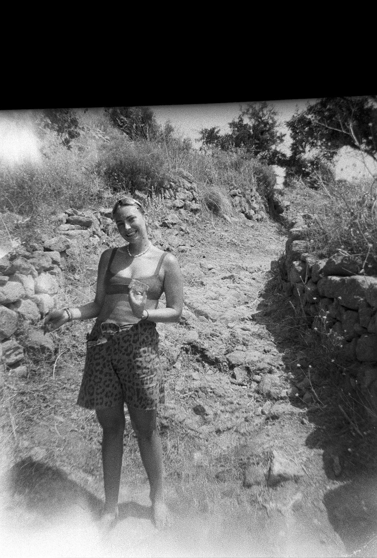 Black and white film photo of Meg on a hillside trail