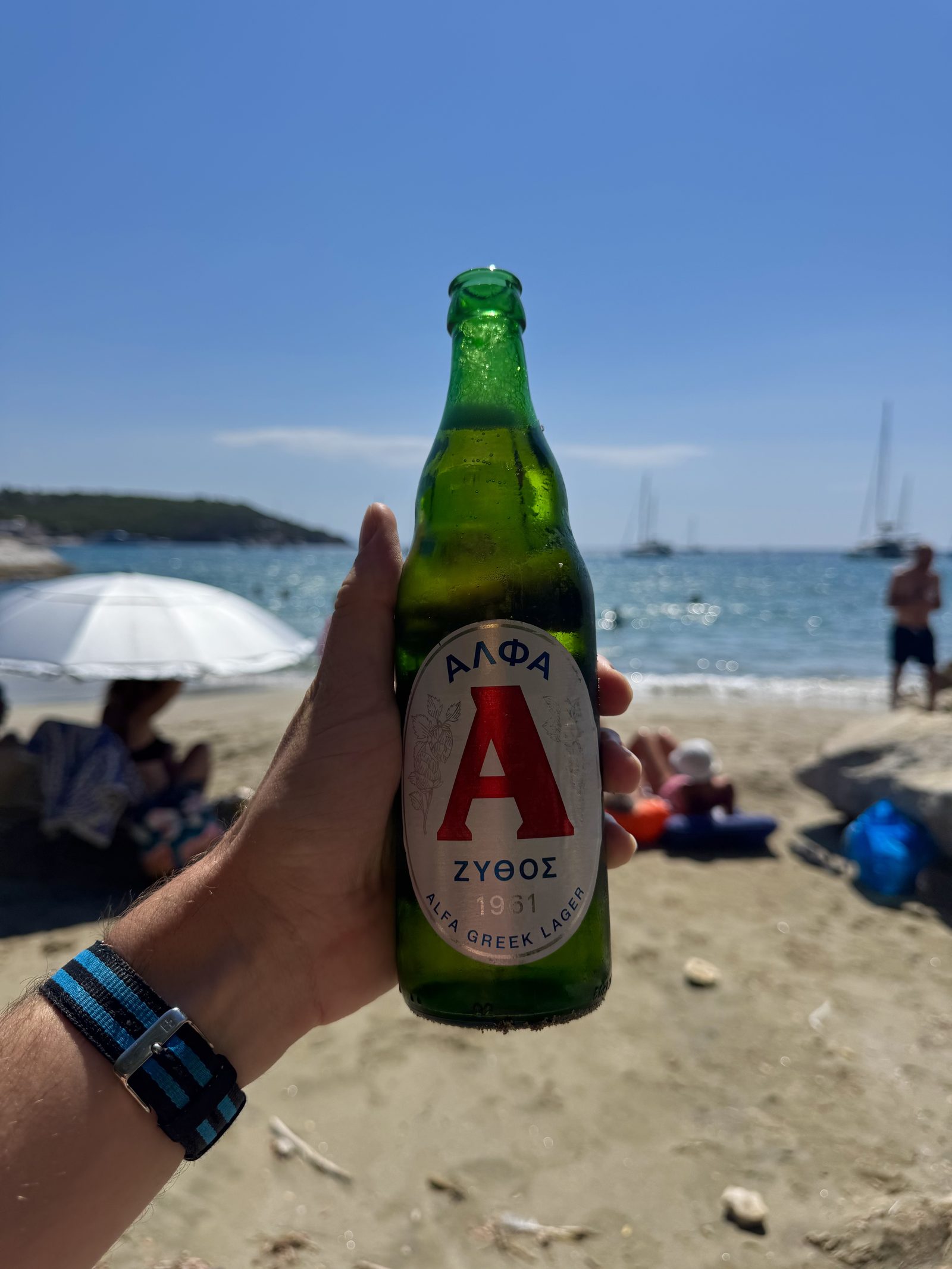 A green bottle of Greek lager on the beach