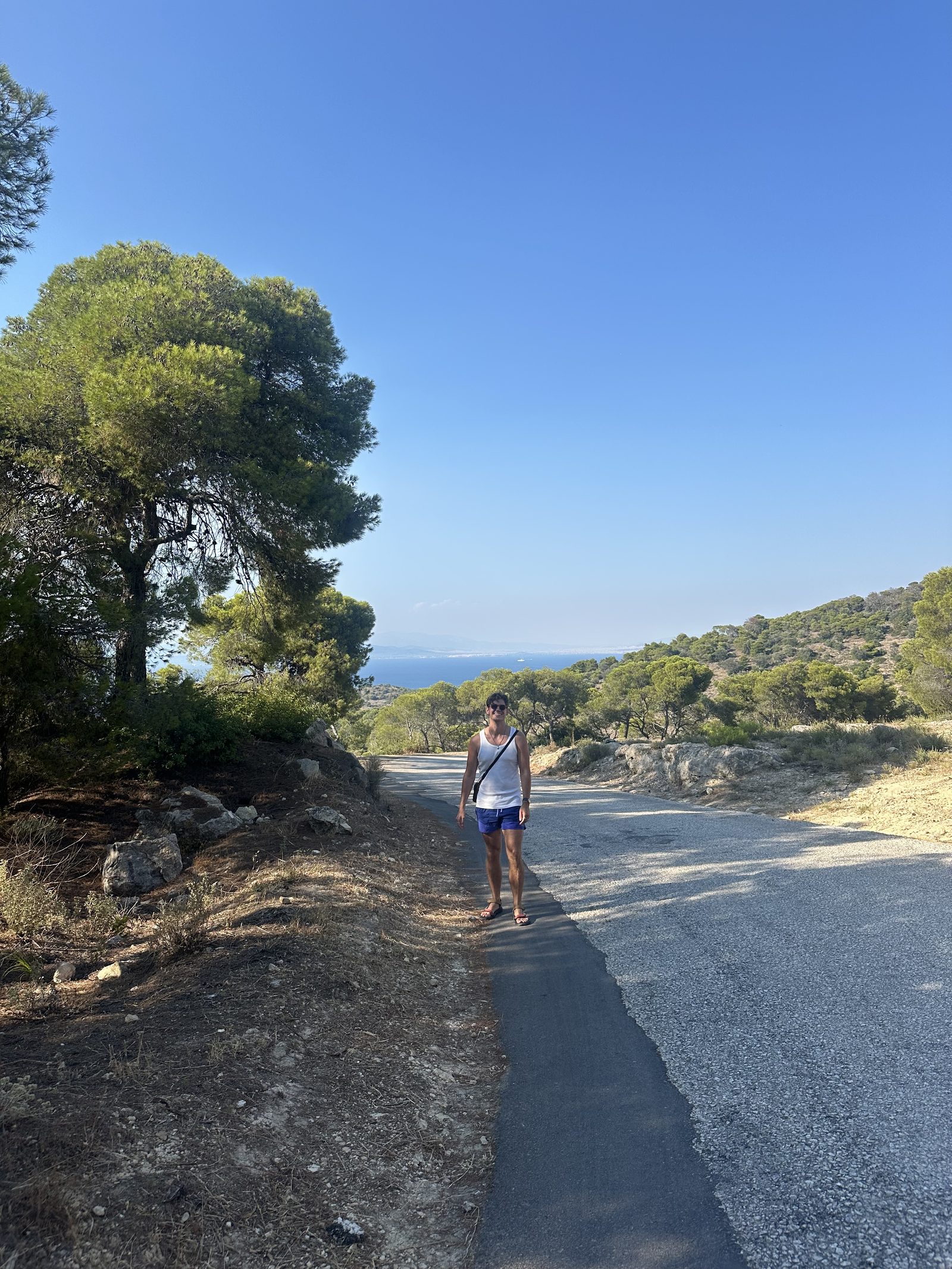 Ryker in a white tank walking on a coastal road