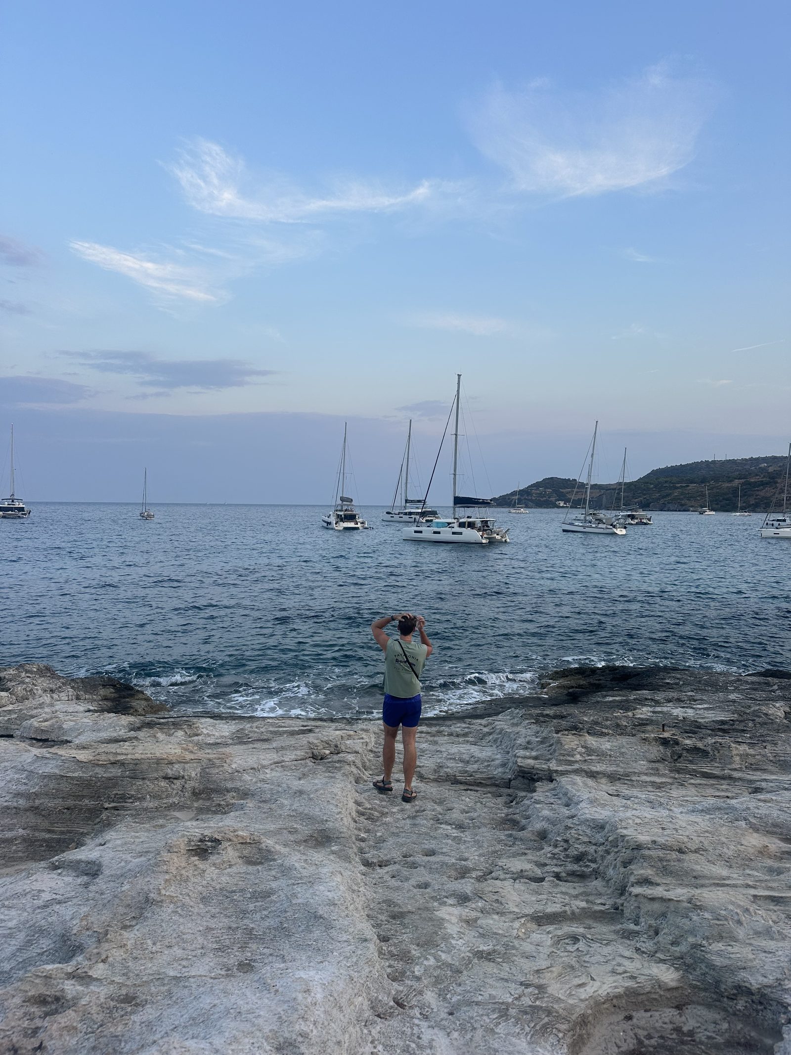 Ryker on a rock beach with boats on the sea