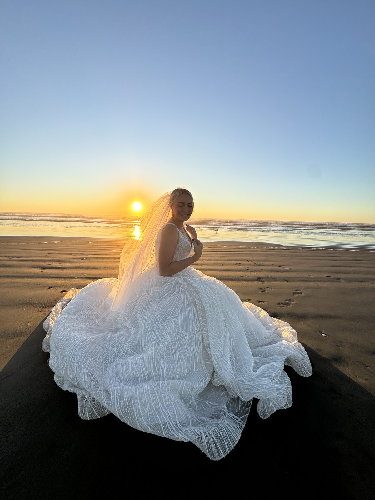 Meg in wedding dress on beach at sunset